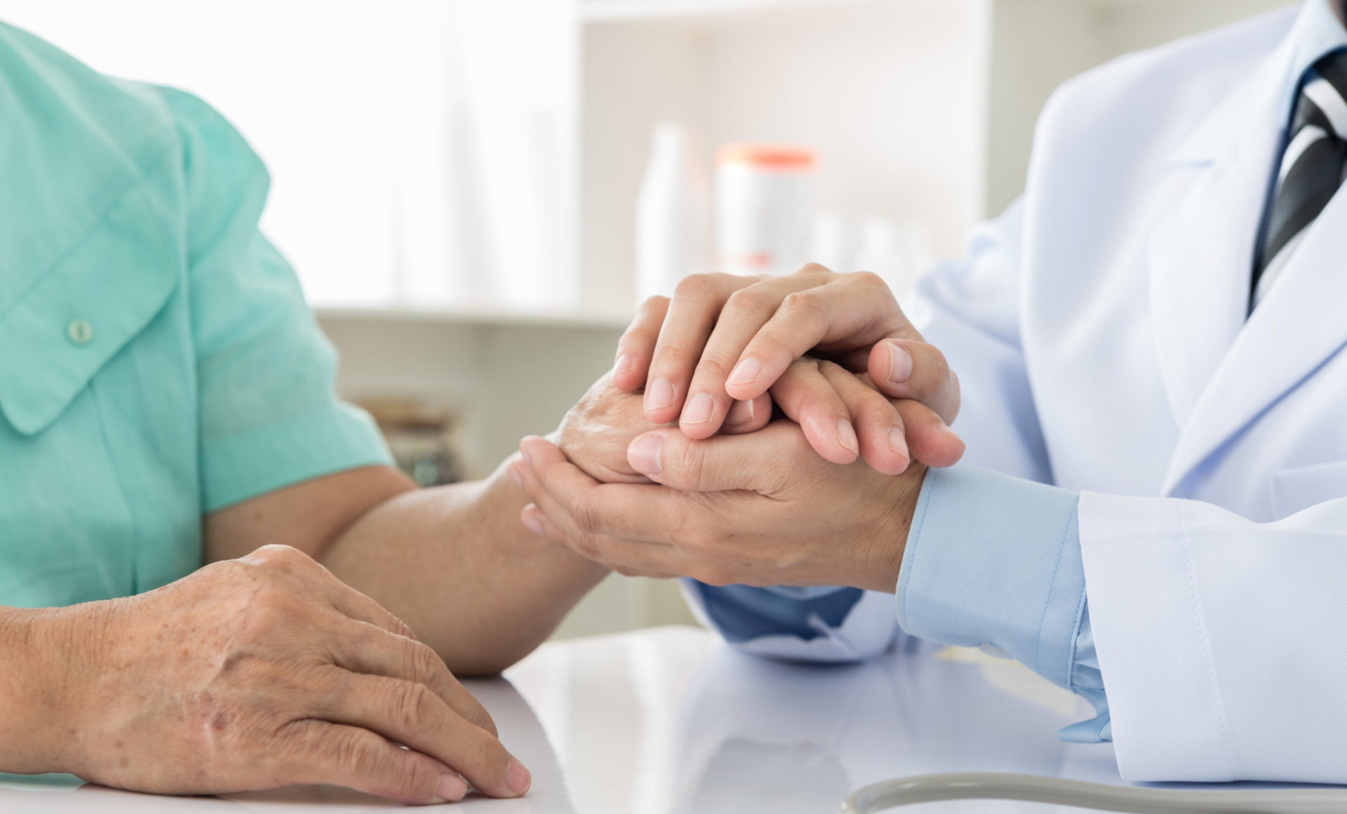Profissional de saúde da Unimed segurando a mão de uma paciente durante uma consulta.