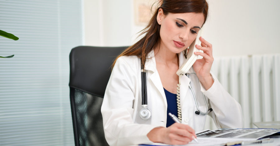 Médica atendendo ao telefone enquanto analisa exames.