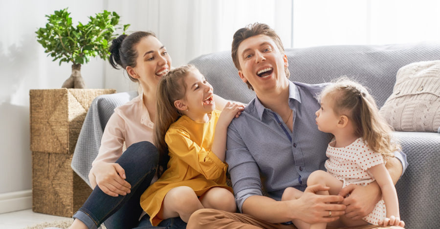 Família reunida e sorrindo na sala de casa.